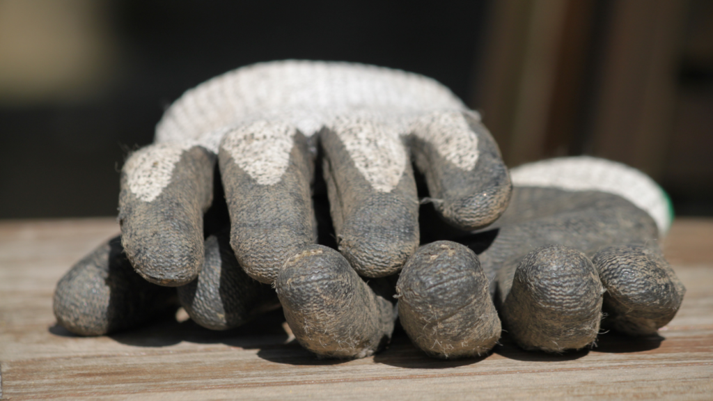 Luva de jardinagem antiderrapante apoiada sobre bancada de madeira para uso em horta de apartamento.
