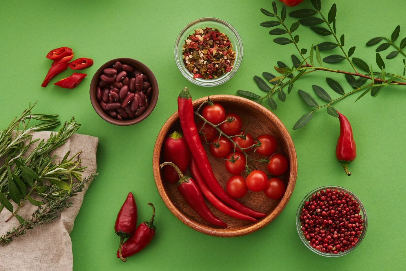 Pimentas, tomates-cereja e ervas arrumados sobre fundo verde