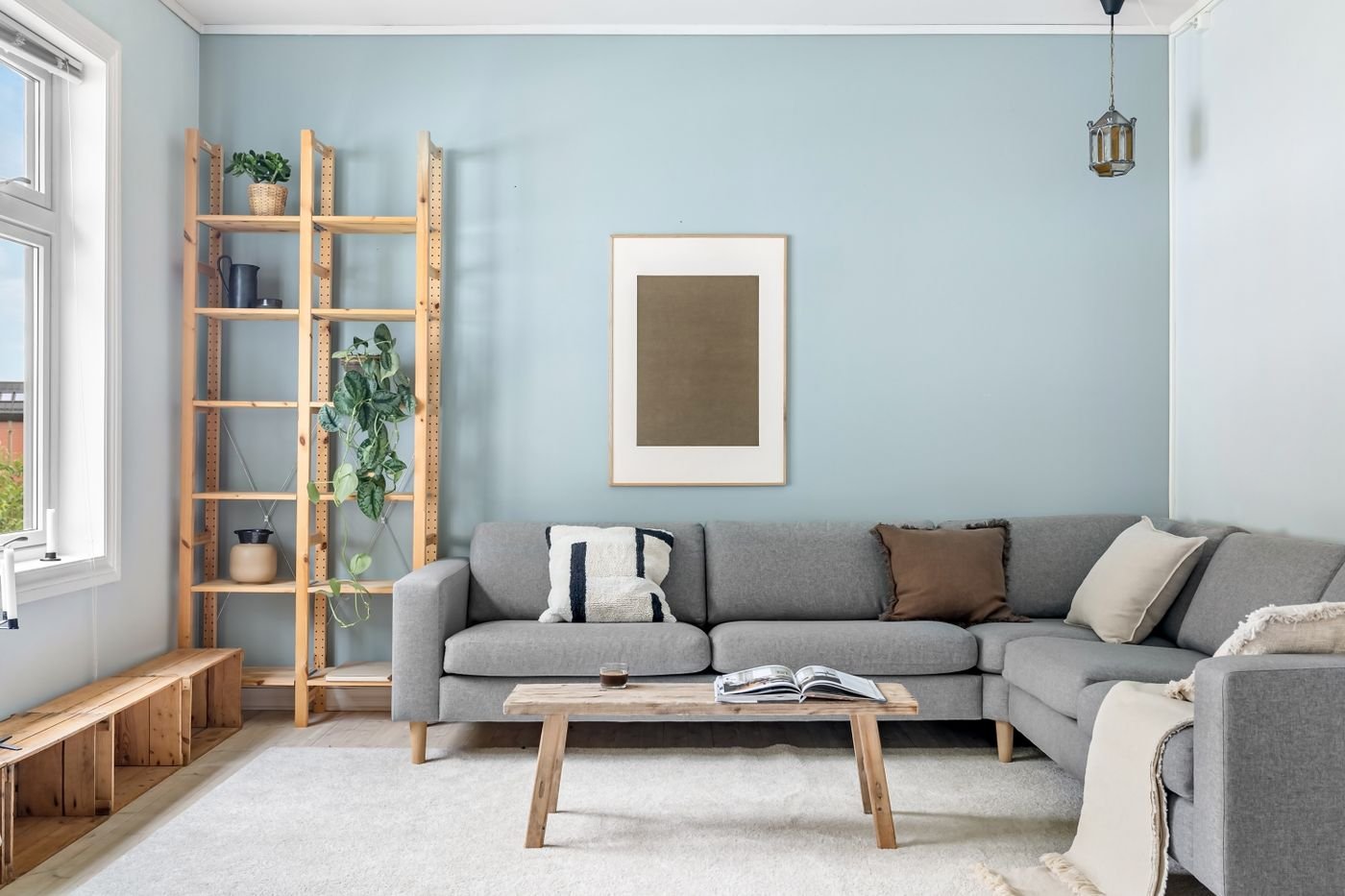 Sala no estilo escandinavo com sofá cinza e móveis de madeira clara