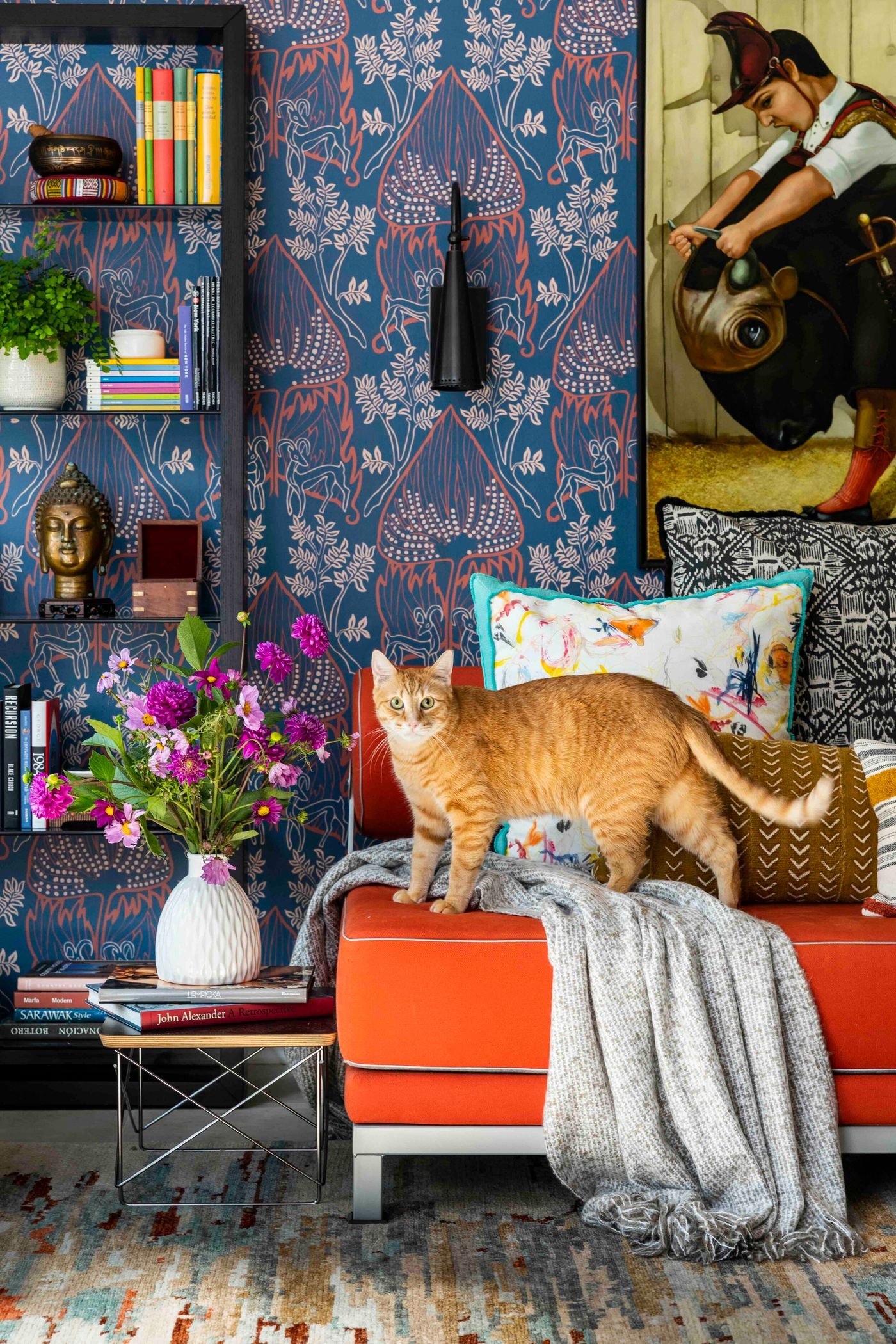 Sala no estilo maximalista com cores vivas, flores e um gato no sofá