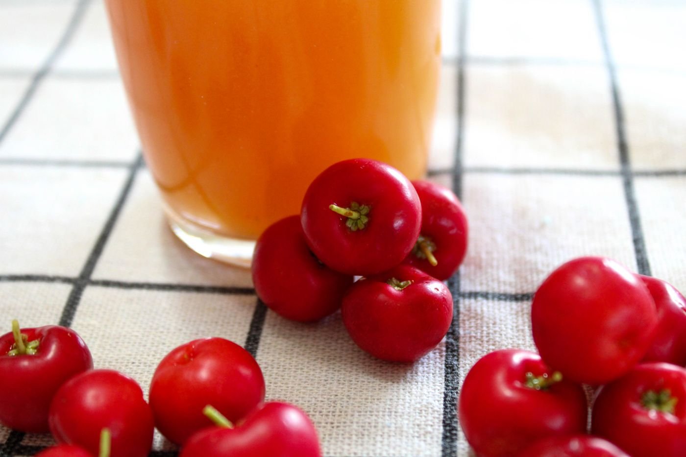 Copo de suco vermelho com frutas frescas ao lado sobre a toalha