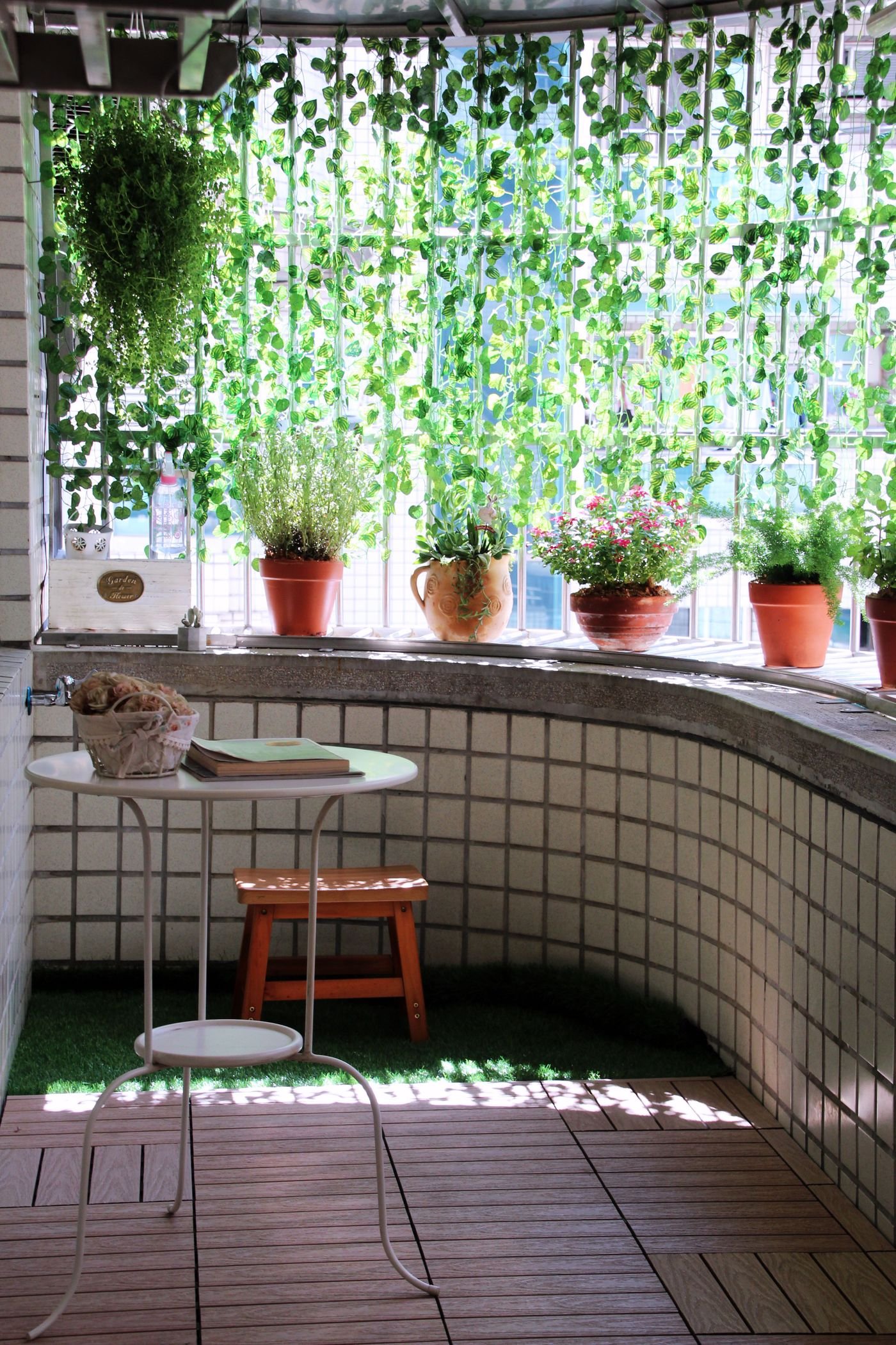 Varanda ensolarada com vasos de plantas e uma mesinha